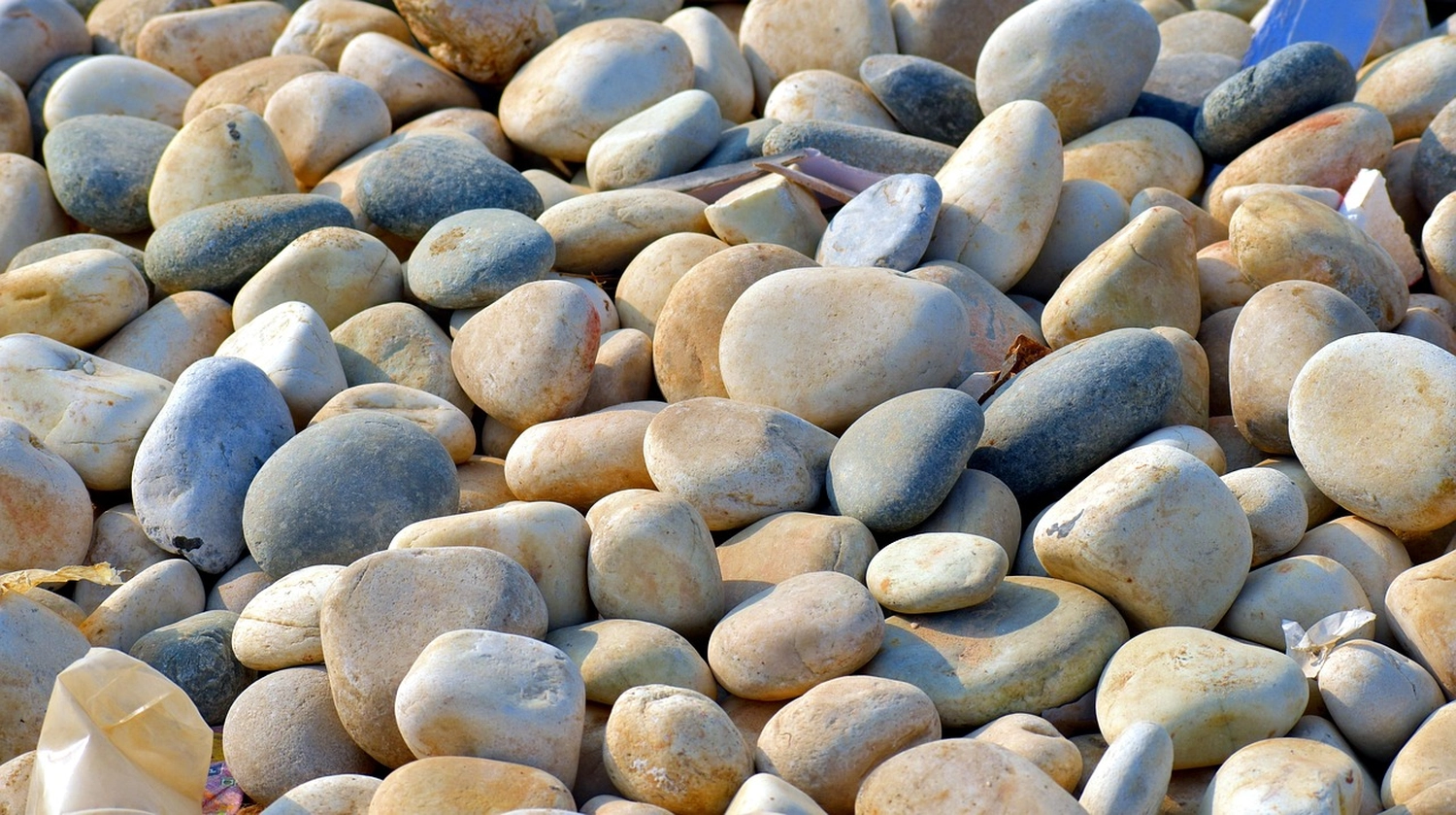 Mindtrail - Coaching und Mentoring - Eine Nahaufnahme eines Haufens glatter, abgerundeter Flusssteine in verschiedenen natürlichen Farben wie Grau, Beige und Braun.